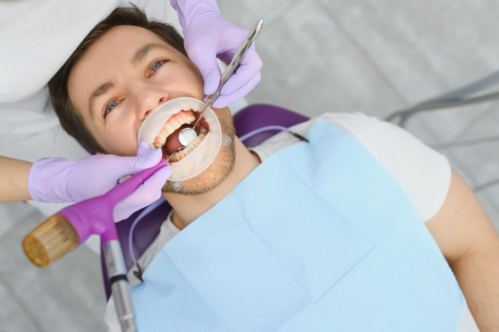 periodontal services closeup shot of smiling man getting treatment in stomatologic clinic