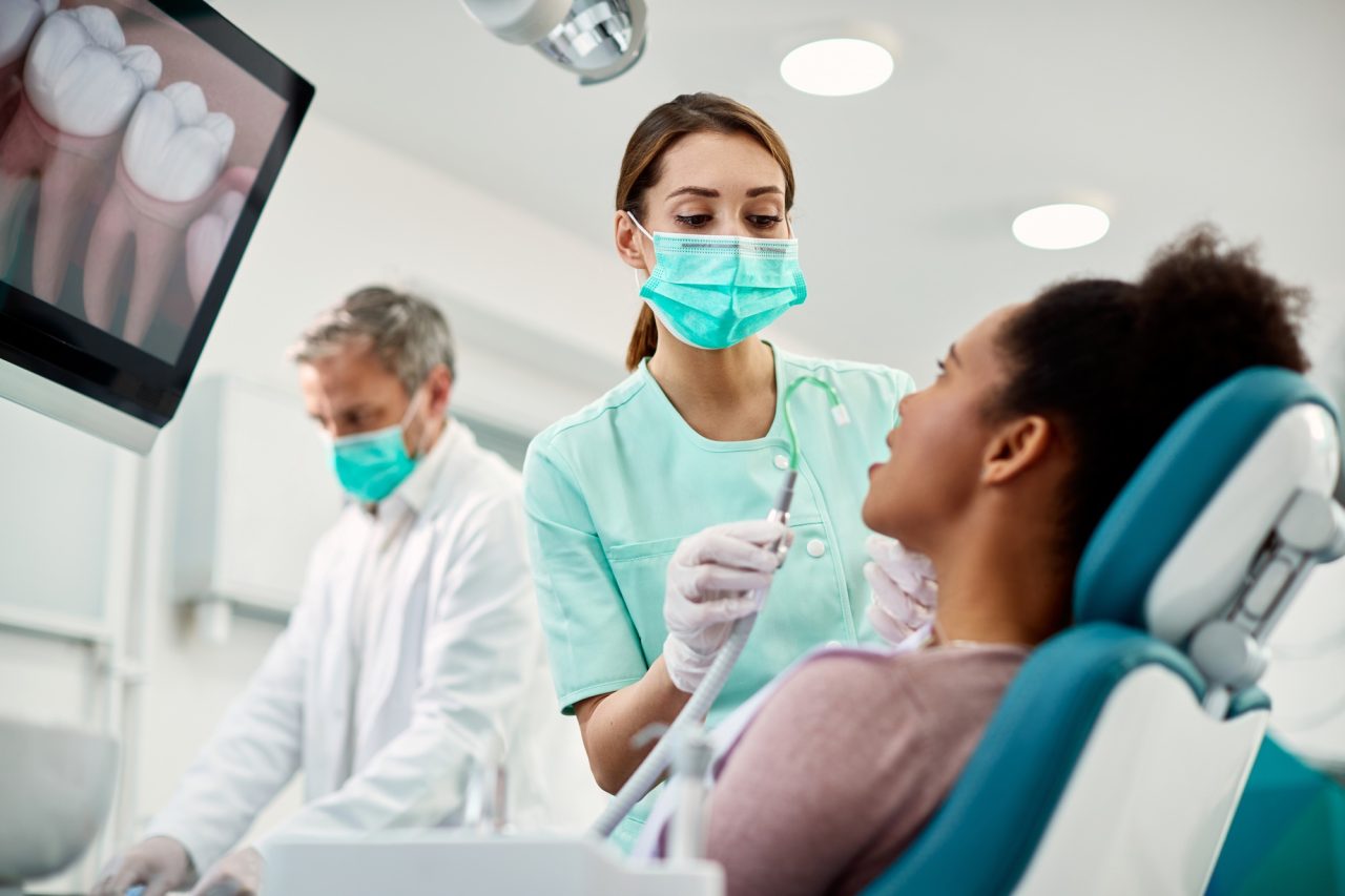 young nurse preparing patient for dental procedure at dentist s office
